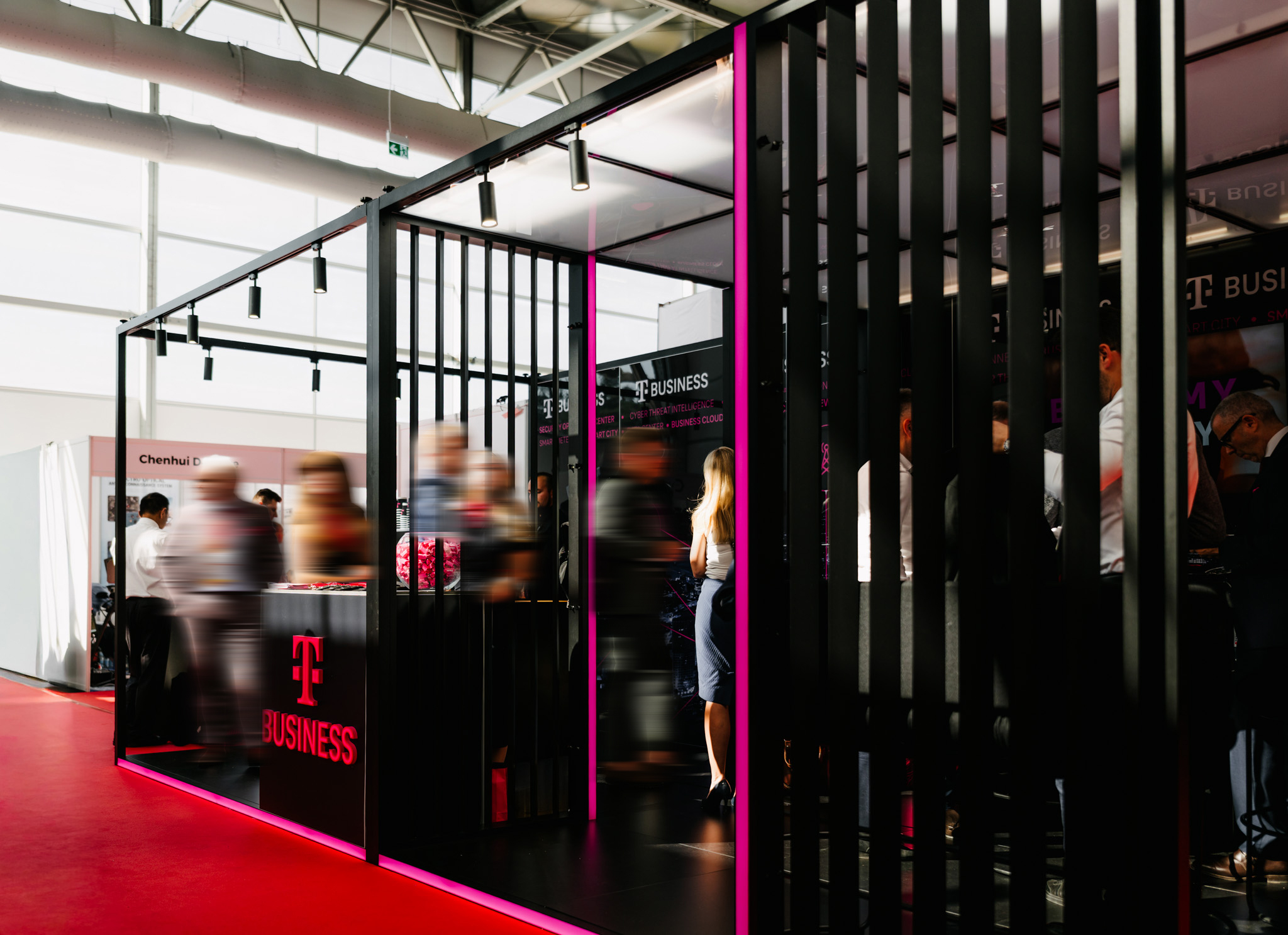 T-Mobile trade show stand in black and magenta, featuring slatted elements and linear floor lighting